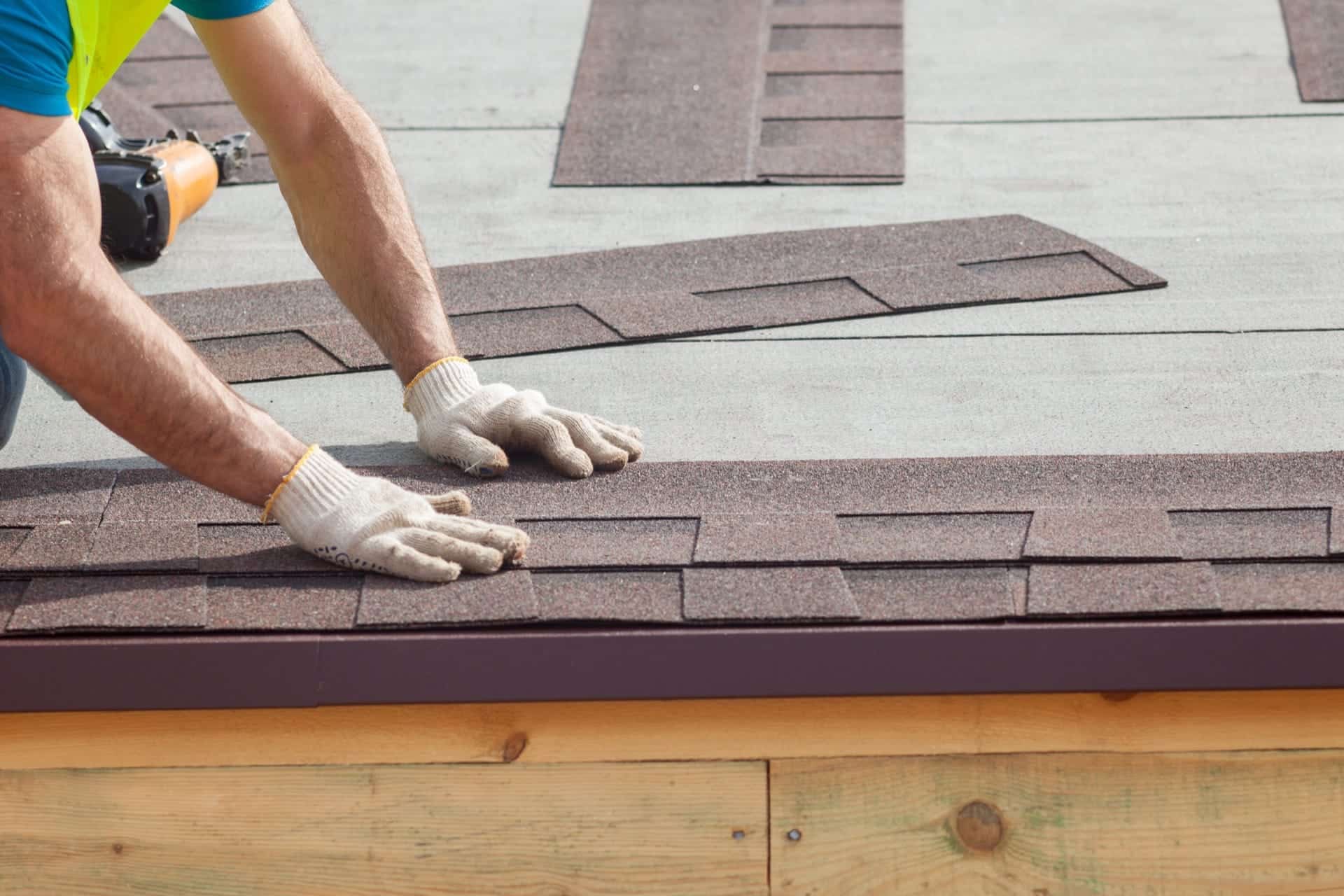 A roofer lays shingles